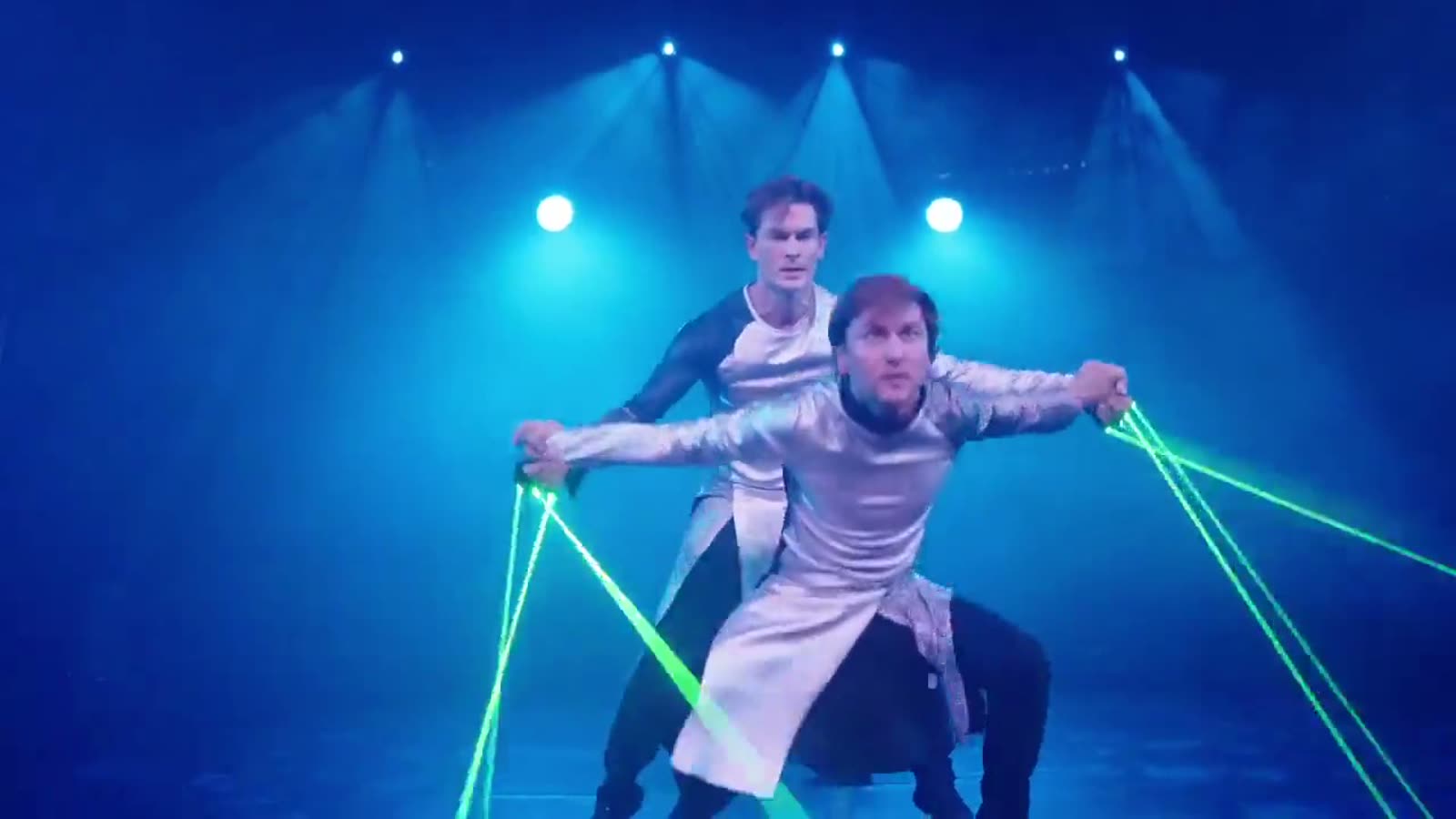 Jim & John in silbernen Futuristik-Kostümen, aus ihren Handschuhen laufen grüne Laserstrahlen in den blau ausgeleuchteten Raum